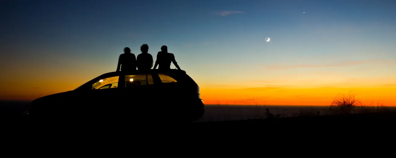 Guys watching sunset from top of car