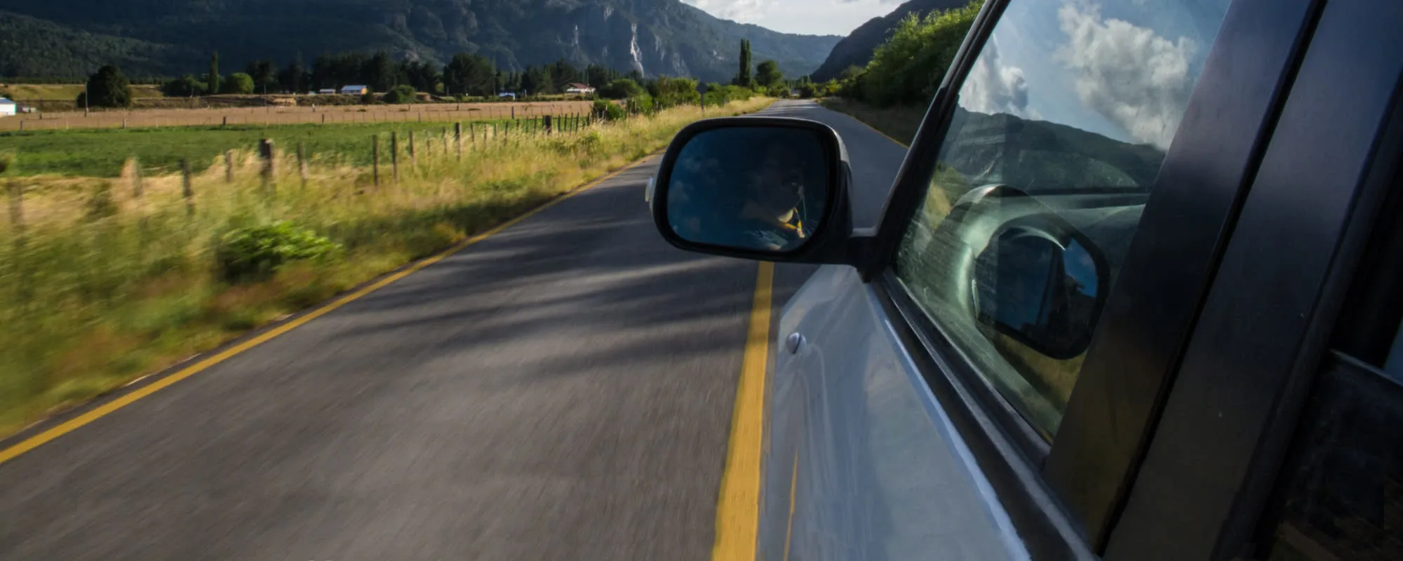 Windscreen side mirror view on road