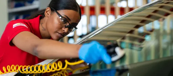 Välkomstbild på en kvinna på Carglass verkstad  som lagar en vindruta
